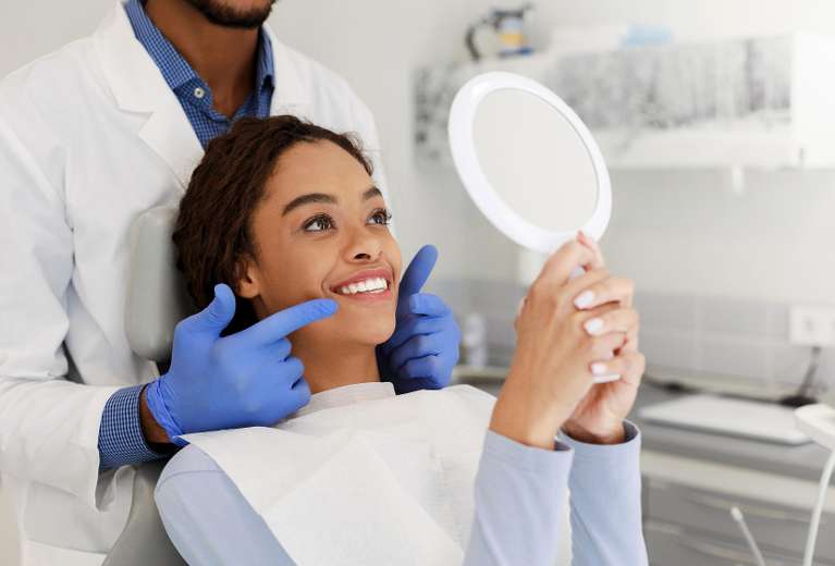 patient looking in mirror after smile makeover tampa