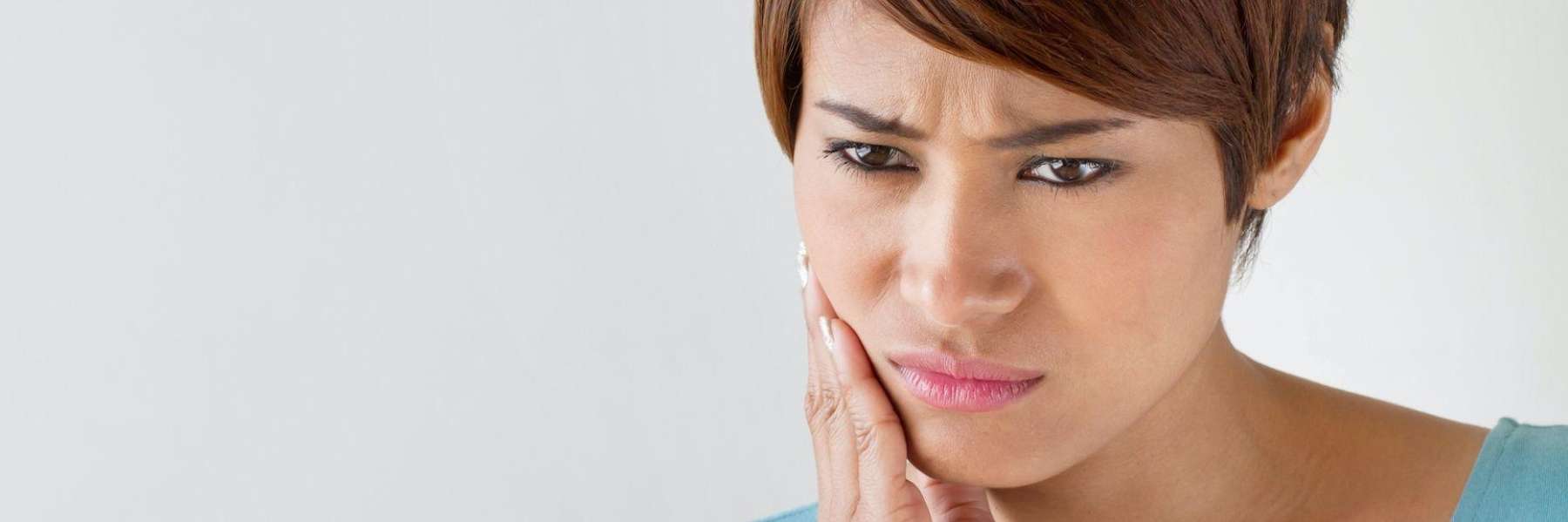 woman holding her right cheek